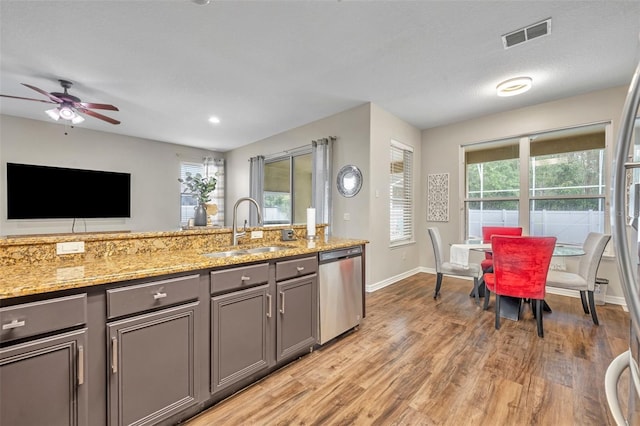 kitchen featuring visible vents, light wood-style flooring, gray cabinets, a sink, and dishwasher