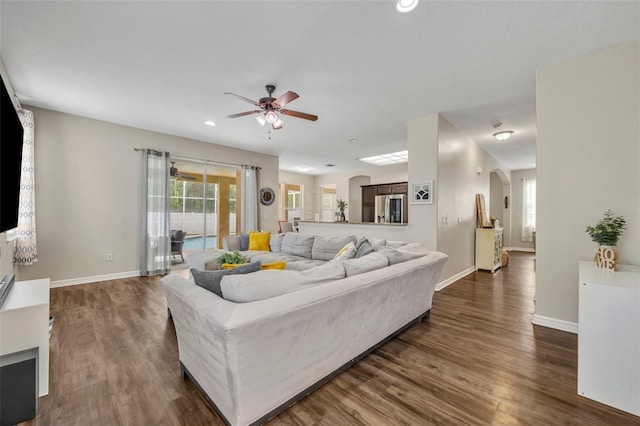 living area with dark wood finished floors, arched walkways, and baseboards