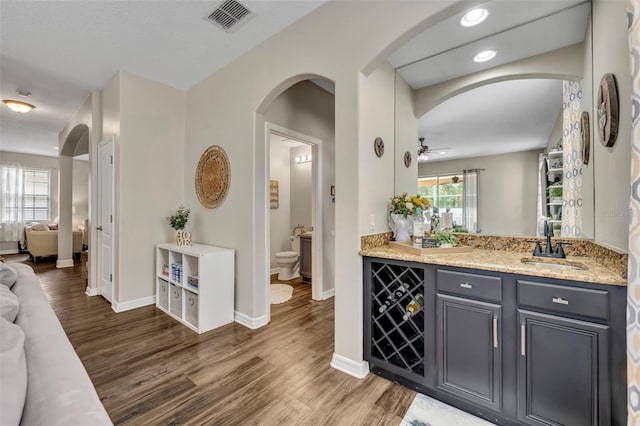 bar with arched walkways, visible vents, a sink, and wood finished floors