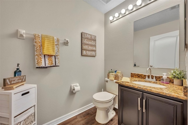 half bath featuring toilet, vanity, baseboards, and wood finished floors