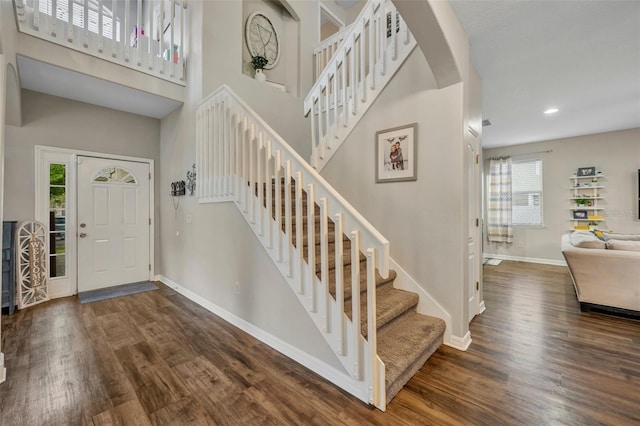 entryway with stairway, a high ceiling, baseboards, and wood finished floors