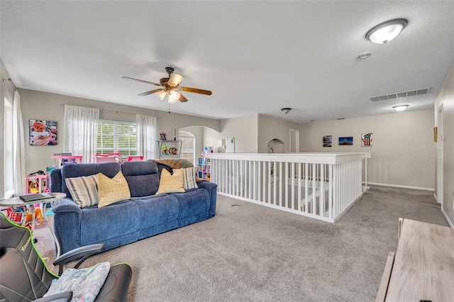 living area with arched walkways, visible vents, baseboards, and carpet