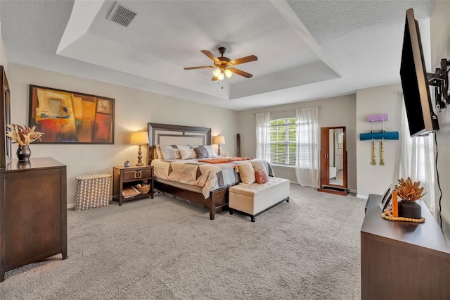 bedroom featuring visible vents, baseboards, carpet, a tray ceiling, and a textured ceiling