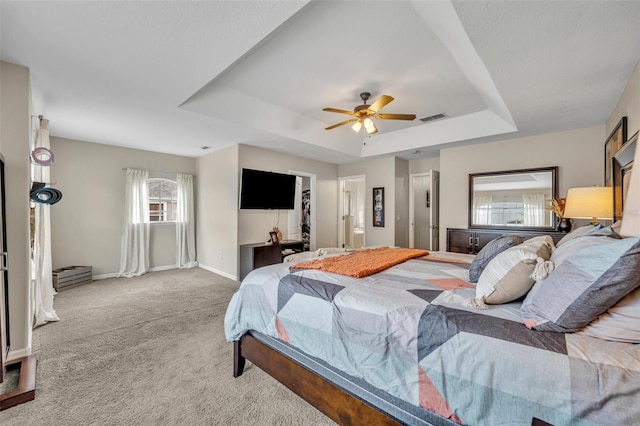 carpeted bedroom with visible vents, ceiling fan, a raised ceiling, and baseboards