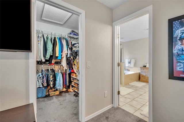 interior space featuring tile patterned flooring, carpet flooring, and attic access