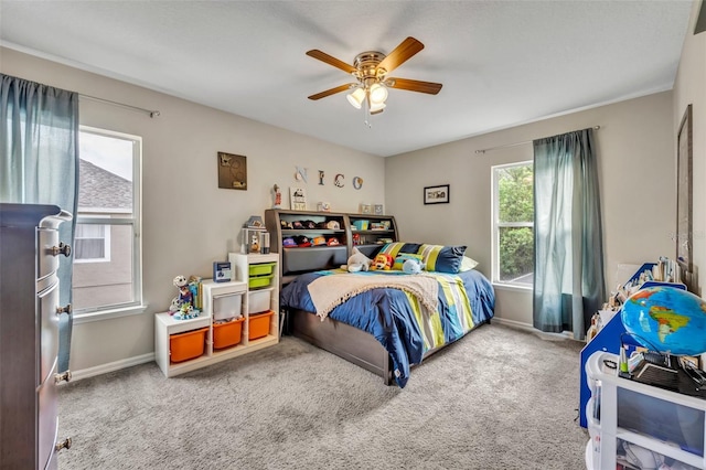 carpeted bedroom with ceiling fan and baseboards