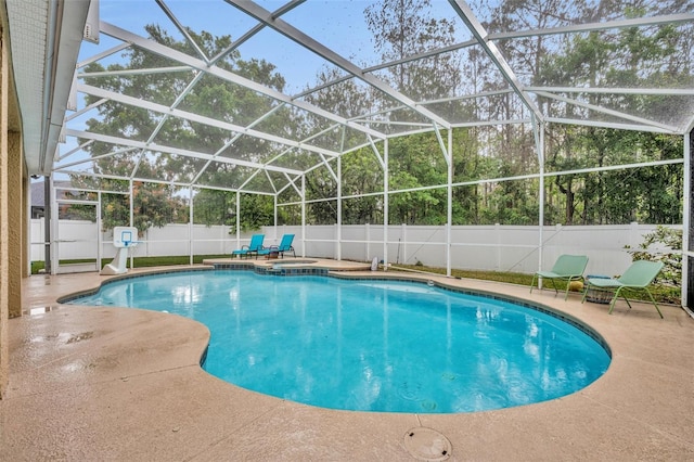 view of pool featuring glass enclosure, a patio, a fenced backyard, and a pool with connected hot tub