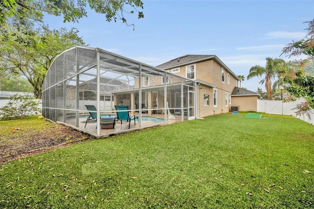 rear view of property with stucco siding, a lawn, central AC, a fenced backyard, and a patio area