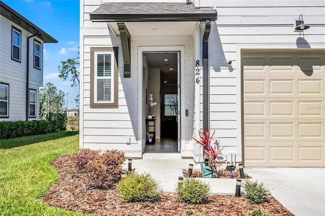 property entrance with a garage, a yard, and roof with shingles