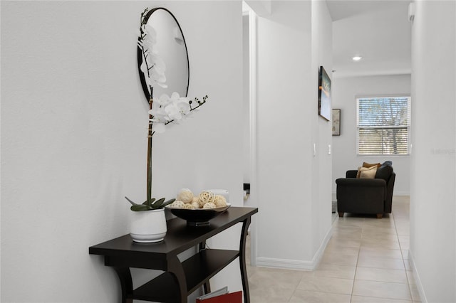 hall featuring light tile patterned floors and baseboards