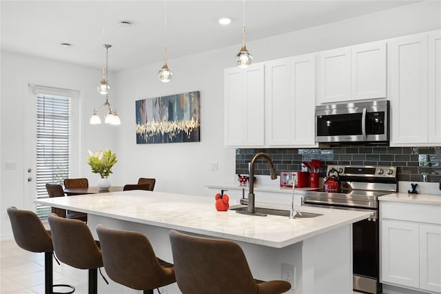 kitchen featuring backsplash, appliances with stainless steel finishes, a kitchen breakfast bar, white cabinets, and a sink