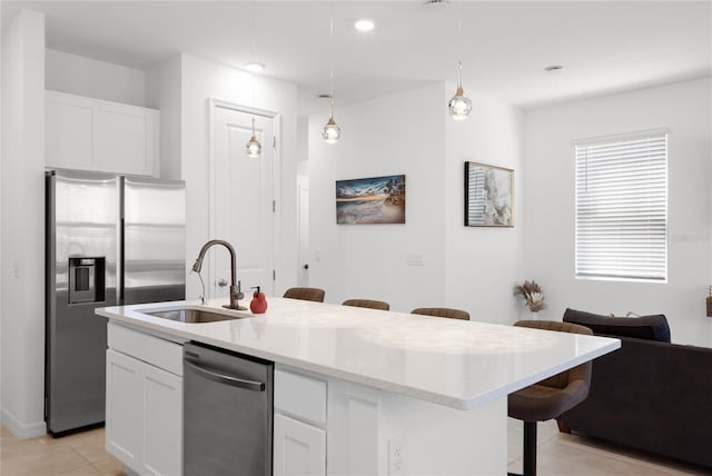 kitchen featuring white cabinets, appliances with stainless steel finishes, a breakfast bar, and a sink