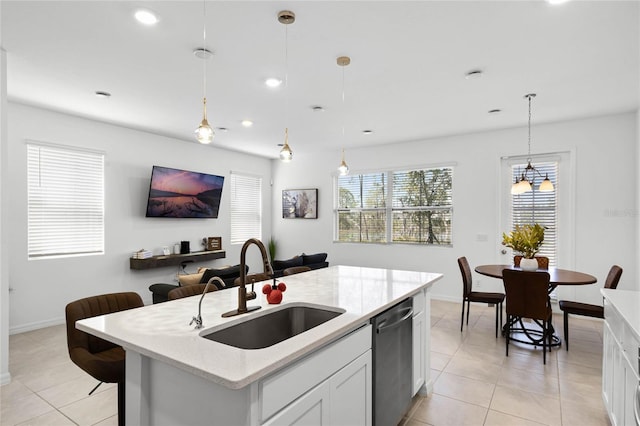 kitchen with light stone countertops, a sink, white cabinets, pendant lighting, and stainless steel dishwasher