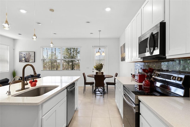 kitchen with a sink, backsplash, stainless steel appliances, light tile patterned flooring, and white cabinets