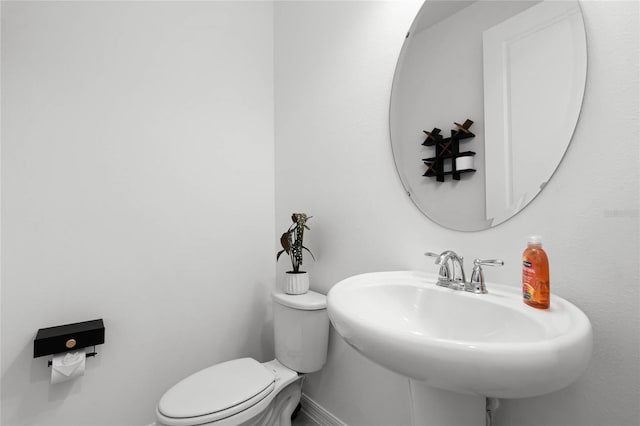 bathroom featuring toilet, baseboards, and a sink