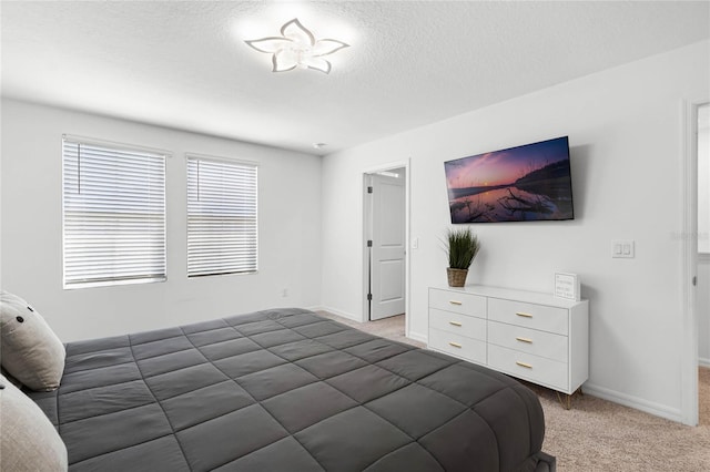 bedroom with light carpet, a textured ceiling, and baseboards