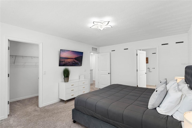 carpeted bedroom featuring a walk in closet, baseboards, visible vents, and a closet