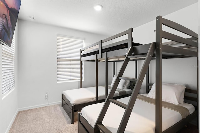 bedroom featuring carpet flooring, a textured ceiling, and baseboards