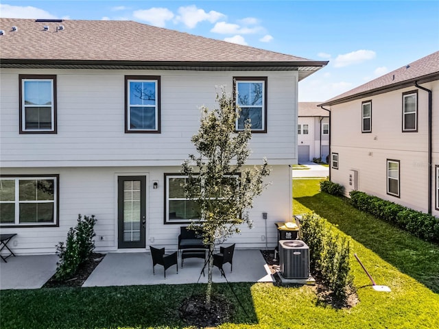 back of property with a yard, a patio, roof with shingles, and central AC unit