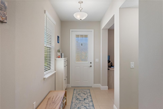 doorway to outside with baseboards and light tile patterned flooring