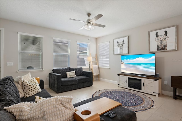 living room with light tile patterned floors, baseboards, a textured ceiling, and a ceiling fan