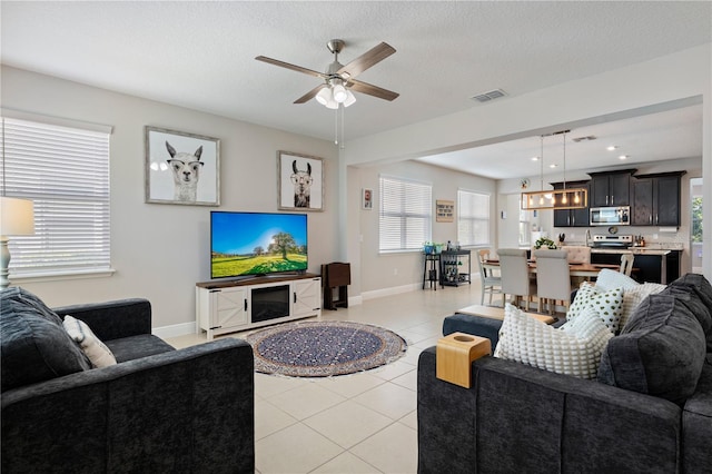 living room featuring light tile patterned floors, visible vents, plenty of natural light, and a textured ceiling