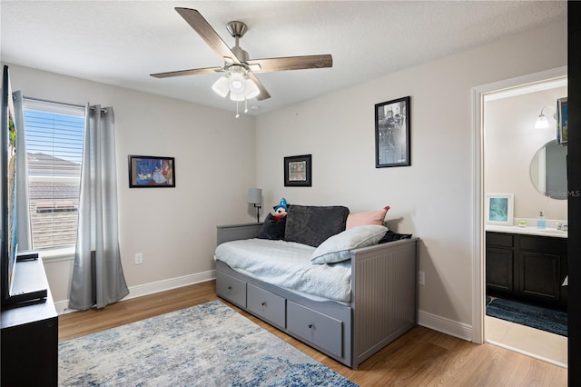 bedroom with ensuite bathroom, baseboards, and wood finished floors