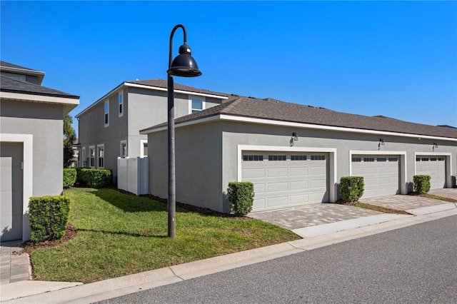 view of side of property featuring a lawn, a garage, and stucco siding