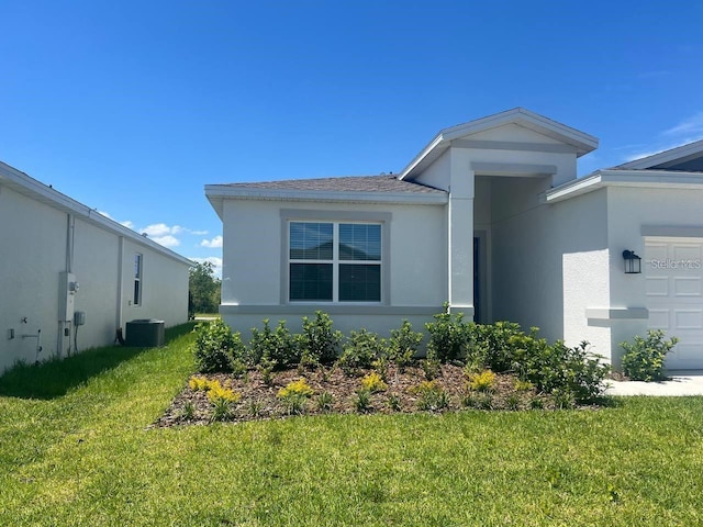 view of front of property with stucco siding, cooling unit, an attached garage, and a front lawn