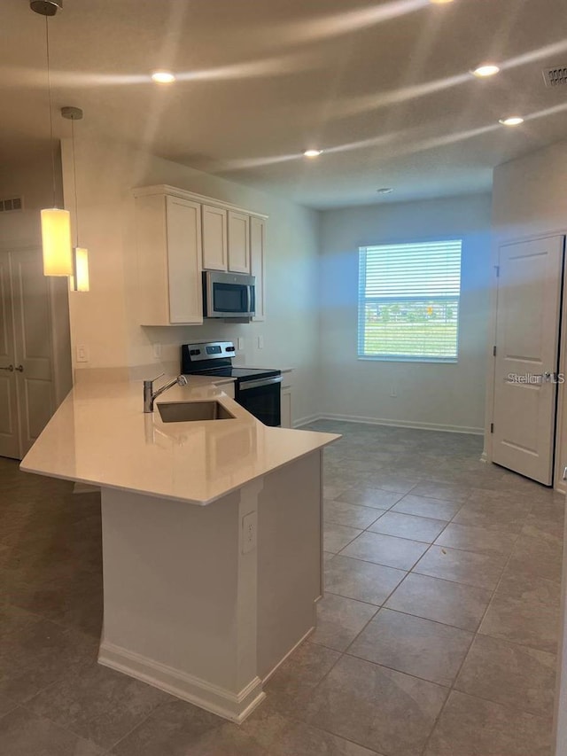 kitchen with a sink, stainless steel appliances, a peninsula, white cabinets, and light countertops