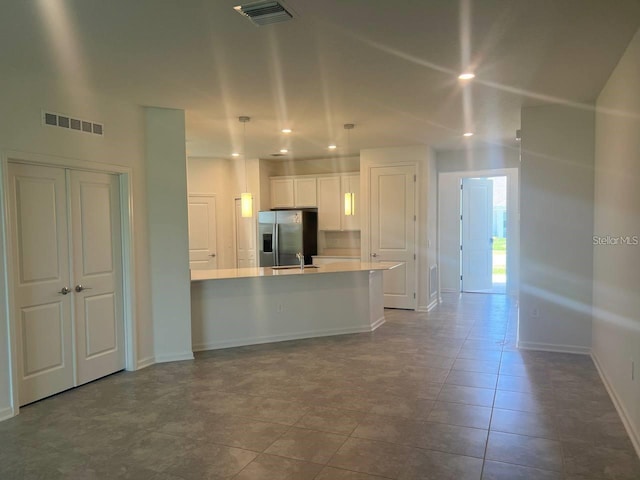 kitchen featuring visible vents, white cabinets, a sink, and stainless steel fridge with ice dispenser