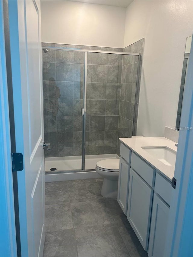 full bathroom with a stall shower, toilet, and vanity