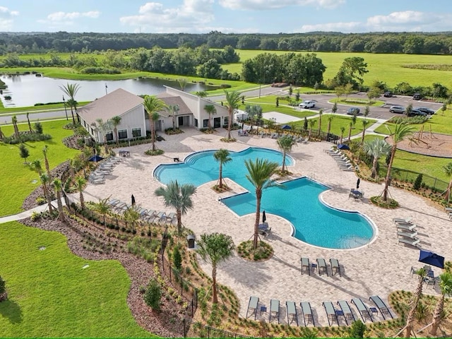 community pool featuring a water view, a patio, and fence