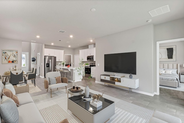 living area featuring recessed lighting, visible vents, and baseboards