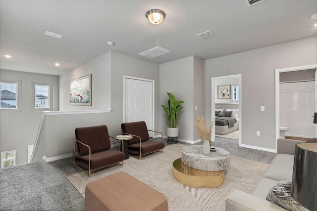 living room featuring baseboards, visible vents, carpet floors, and a textured ceiling