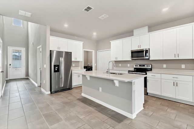 kitchen with a center island with sink, visible vents, a sink, stainless steel appliances, and light countertops