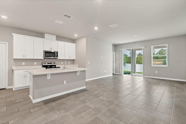 kitchen featuring visible vents, open floor plan, a center island with sink, light countertops, and stainless steel appliances