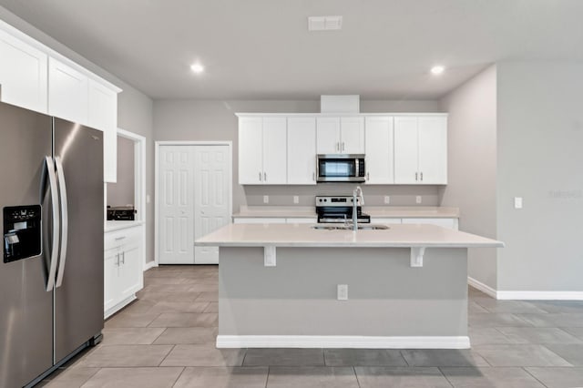 kitchen with light countertops, a center island with sink, appliances with stainless steel finishes, and a sink