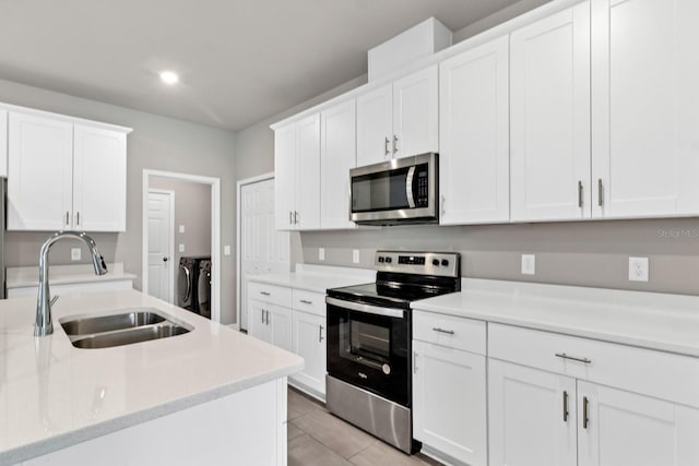 kitchen with washing machine and clothes dryer, a sink, stainless steel appliances, light countertops, and white cabinets