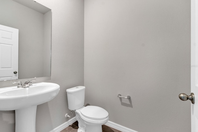 half bath with a sink, baseboards, and toilet