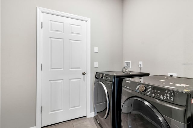clothes washing area featuring laundry area, baseboards, and washing machine and clothes dryer
