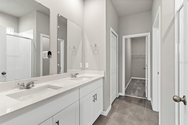 bathroom with a sink, a walk in closet, a stall shower, and double vanity