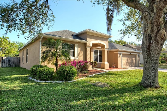 view of front facade with stucco siding, a front yard, a garage, and fence