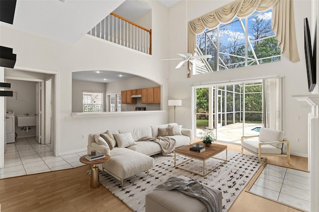 living area featuring washer / dryer, a towering ceiling, baseboards, and light wood finished floors