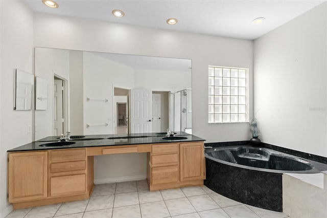 bathroom featuring a bath, double vanity, and a sink