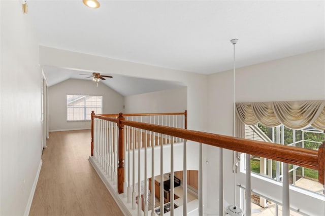 hall with baseboards, light wood-type flooring, and lofted ceiling