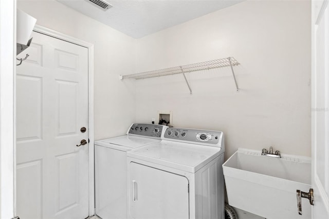 washroom with laundry area, visible vents, independent washer and dryer, and a sink