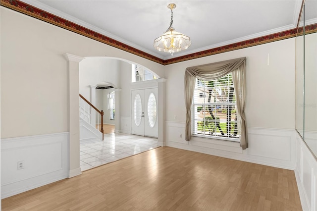 foyer featuring stairway, light wood-style floors, and wainscoting