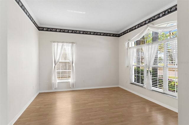 spare room with baseboards, wood finished floors, and ornamental molding