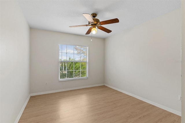 spare room with light wood-style flooring, a ceiling fan, and baseboards